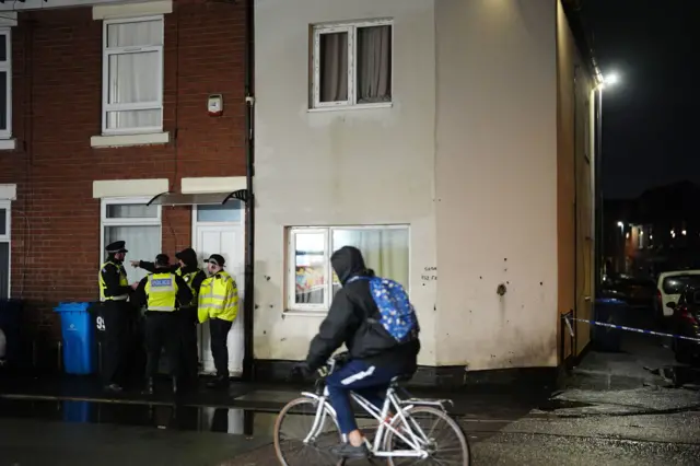 Cyclist going past cordoned-off street in front of police in Derby