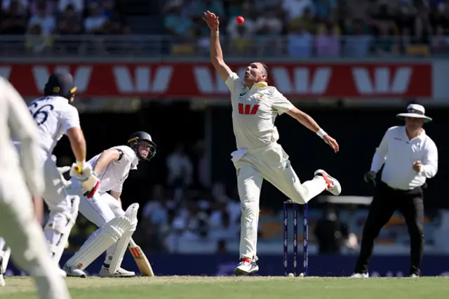 Australia's Scott Boland (C) fields the ball on his own bowling on day one