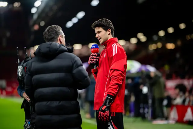 Senne Lammens talks to Gary Neville pitchside