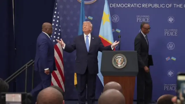 Donald Trump with his arms out, with the Rwandan and DR Congo presidents walking onstage behind him.