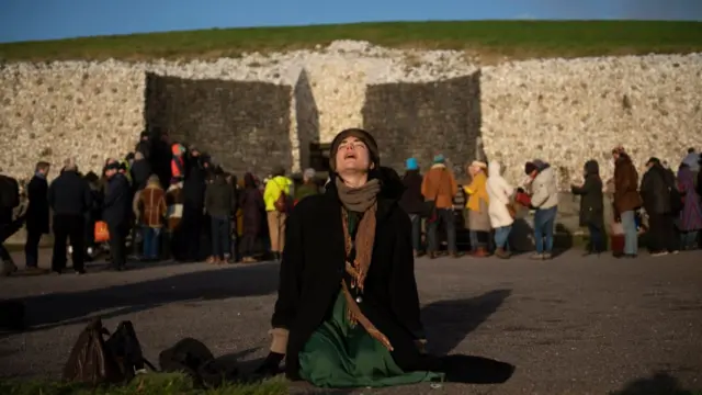 A woman is seen meditating on the floor as people gather to witness the winter solstice on December 21, 2022 in Newgrange, Ireland