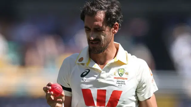 Mitchell Starc looks at the pink ball in his hand
