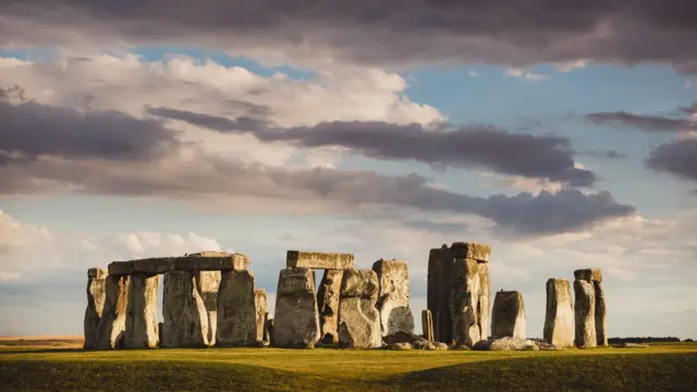 Stonehenge beneath cloudy sky with sunlight coming through