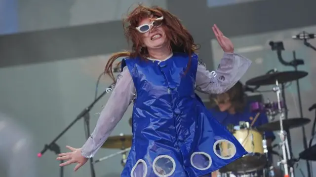 CMAT wearing a blue dress, dancing on stage