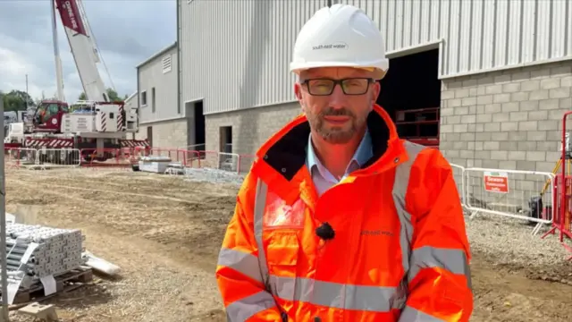 David Hinton in an orange hi-viz suit with a white hard hat.