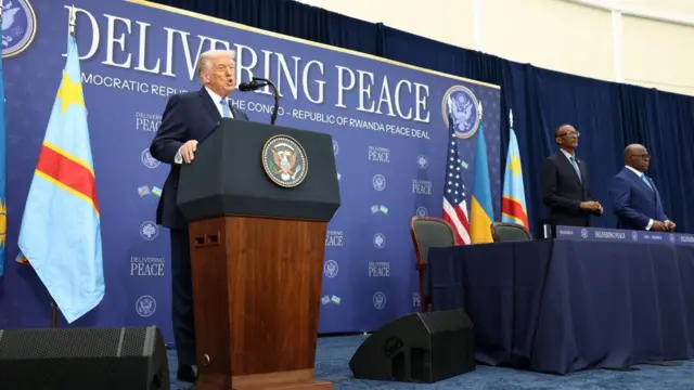 Donald Trump speaks at a lectern with Rwandan President Paul Kagame and DR Congo President Felix Tshisekedi off to one side.