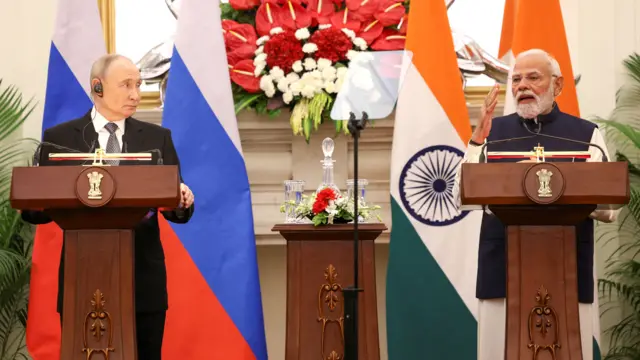 Putin looks at Modi as he speaks