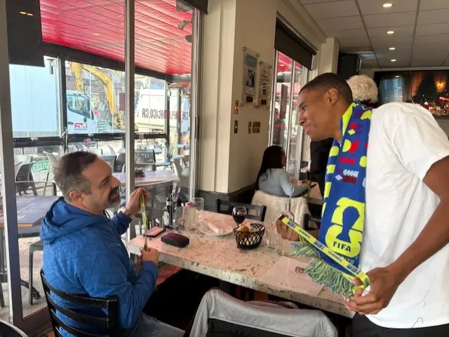 Two football fans in scarves chat across a table