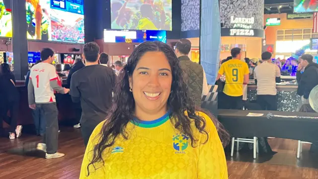 A woman with long dark hair wearing a yellow Brazil football shirt
