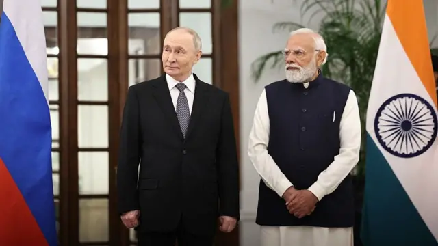 Putin and Modi stand with Russian and Indian flags on either side of them