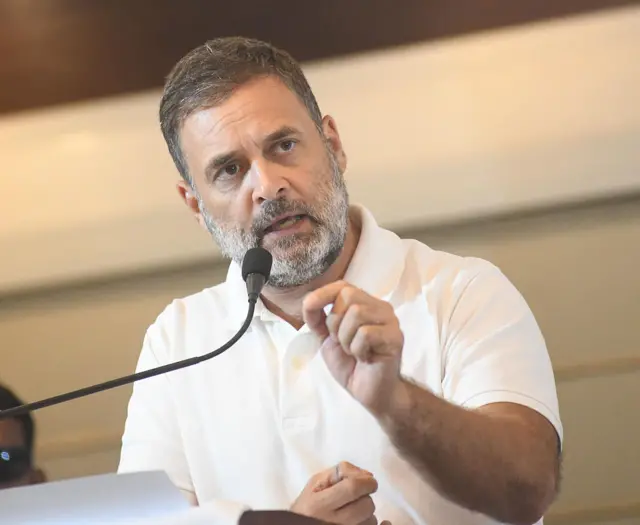 Rahul Gandhi in a white t shirt speaking into a mic