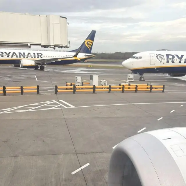The wing of a plane, with other Ryanair planes in the distance
