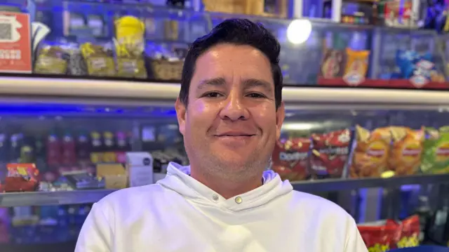 A man in a white hoodie sits in a grocery story