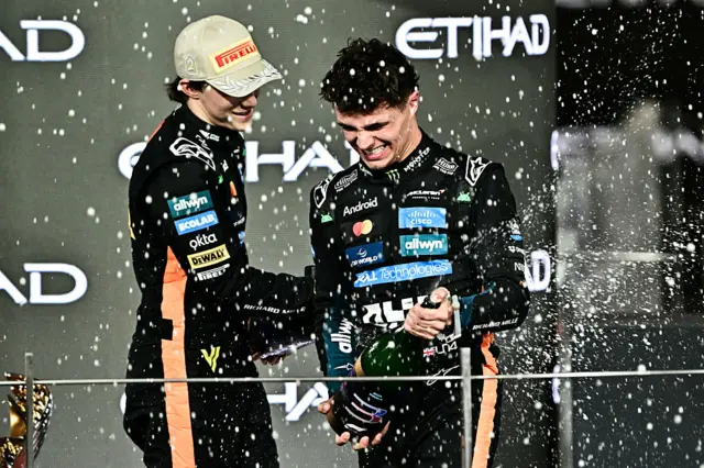 Oscar Piastri and Lando Norris spray champagne on the podium