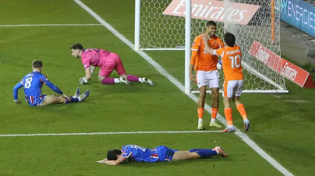 Blackpool players celebrate and Carlisle players look distraught after conceding a goal