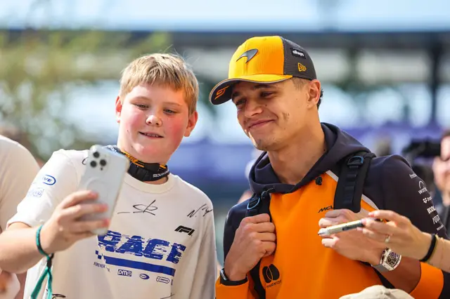 Lando Norris takes a picture with a fan