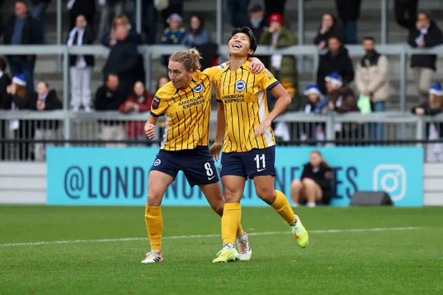 Kiko Seike of Brighton & Hove Albion (R) celebrates scoring her team's first goal with teammate Maisie Symonds (L) during the Barclays Women's Super League match between London City Lionesses and Brighton & Hove Albion at Copperjax Community Stadium on December 07, 2025 in Bromley, England.
