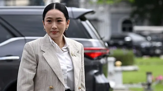 Paetongtarn Shinawatra wearing a grey blazer standing near a black car