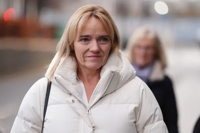 a woman with blonde shoulder-length hair is wearing a cream coloured winter jacket