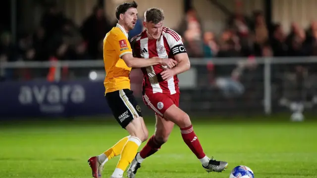 Burton Albion's Jake Beesley (left) and Brackley Town's Gareth Dean battle for the ball