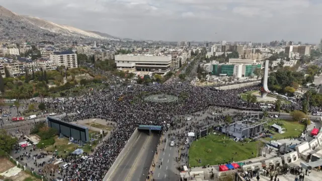 A drone view of a roundabout in Damascus showing a huge gathering of people for the military parade on Monday