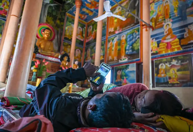 A man and a woman lying on the floor of a temple in Siem Reap, displaced by fighting between Thailand and Cambodia