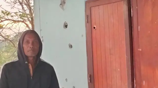 Man stands beside a damaged wall