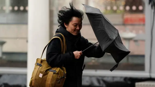 A person struggles to hold an umbrella during strong winds in Birmingham