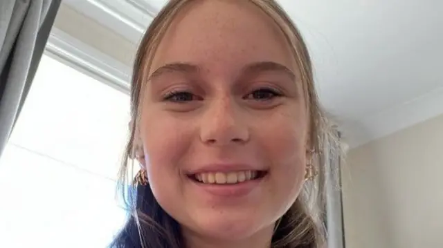 Emily looks to camera and smiles