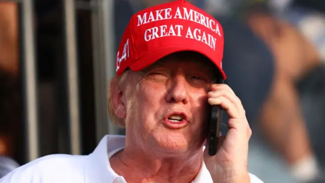 Donald Trump wearing red MAGA hat talking on the phone