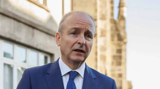 Martin has grey hair and is wearing a navy suit