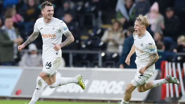Swansea city players celebrate after scoring a goal against Oxford United