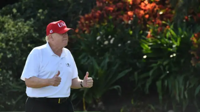 File photo of Donald Trump holding his thumbs up while walking at the golf course in Mar-a-Lago in December 2017