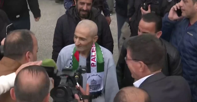 A man in a grey jumper wearing a Palestine scarf