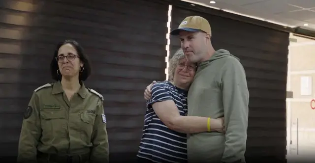 A woman smiling hugging a man who is taller than her