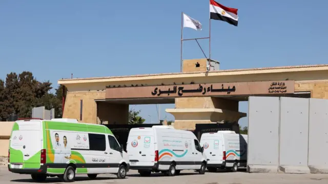 Three ambulances queue at the Rafah border crossing, with one passing through the crossing