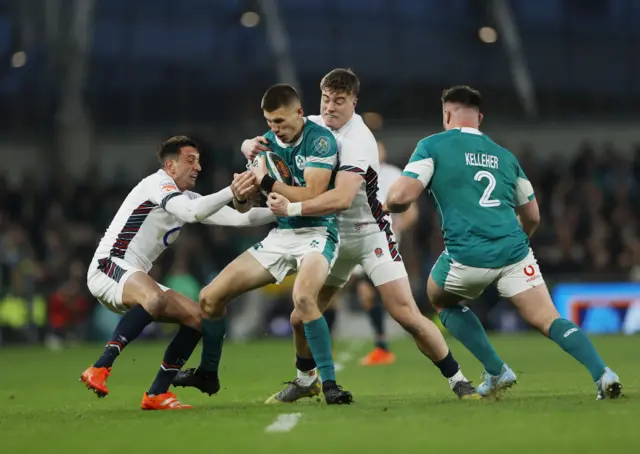 Ireland's Sam Prendergast in action with England's Alex Mitchell and England's Tommy Freeman