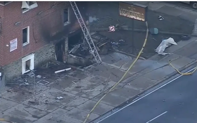 A burnt out building with debris around it and a ladder to an upper window