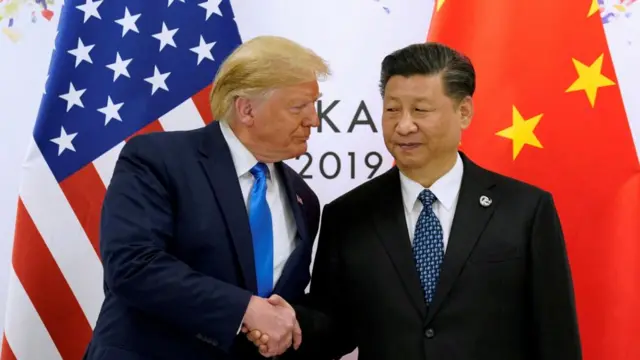 Donald Trump and China's President Xi Jinping shaking hands with US and Chinese flags behind them