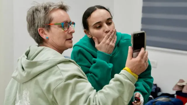 Emily Damari blows a kiss while on FaceTime; her mum, Mandy, holds the phone.