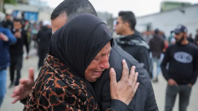 A woman, wearing a brown and black coat and a headscarf, cries and hugs a man after he is released from an Israeli prison