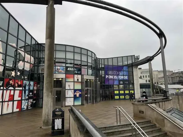 The outside of Ponds Forge sports centre - a building constructed from multiple glass squares. It is up some steps.