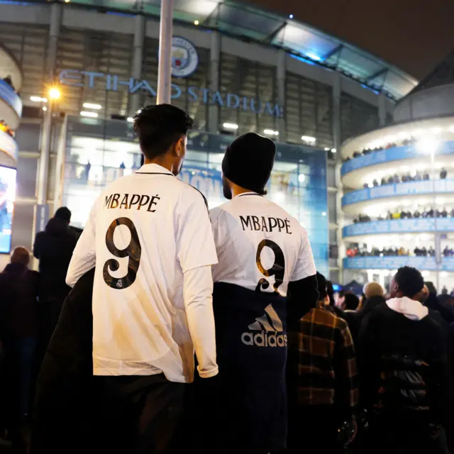 Madrid fans wearing Mbappe tops stand outside Etihad Stadium