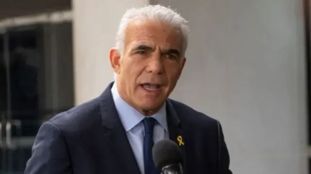 Israeli opposition leader Yair Lapid talking, with mics in front of him.