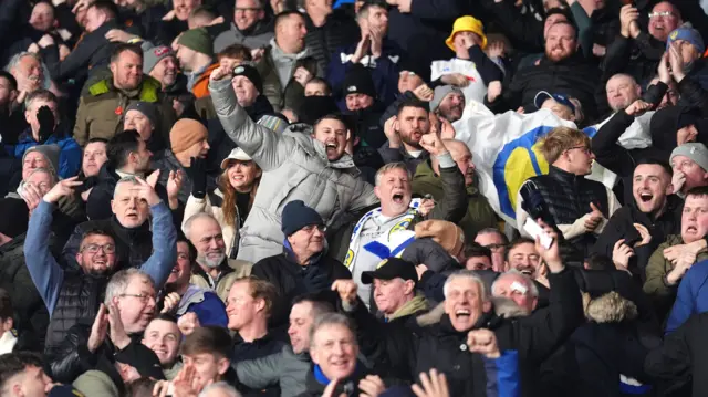 Leeds fans celebrate in the away end at Vicarage Road