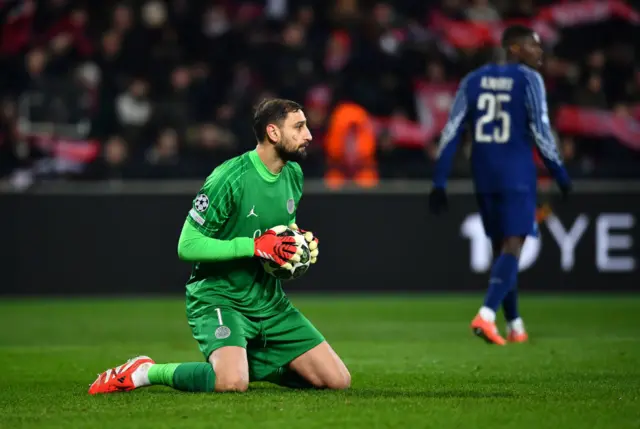 Gianluigi Donnarumma gathers the ball while kneeling on the floor