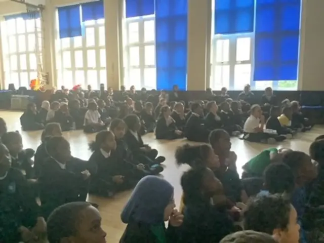 A photograph of children at Oldhill Community School watching the Live Lesson in a hall
