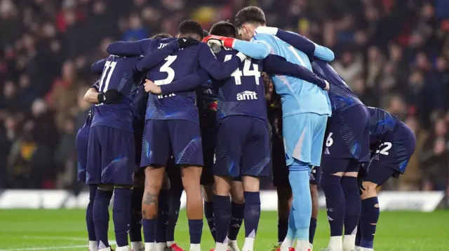 Leeds players huddle at Vicarage Road before kick-off