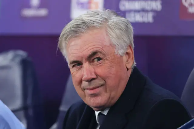 Ancelotti sits and smile in the dugout