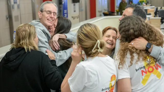 Seven family members smile as they embrace one another